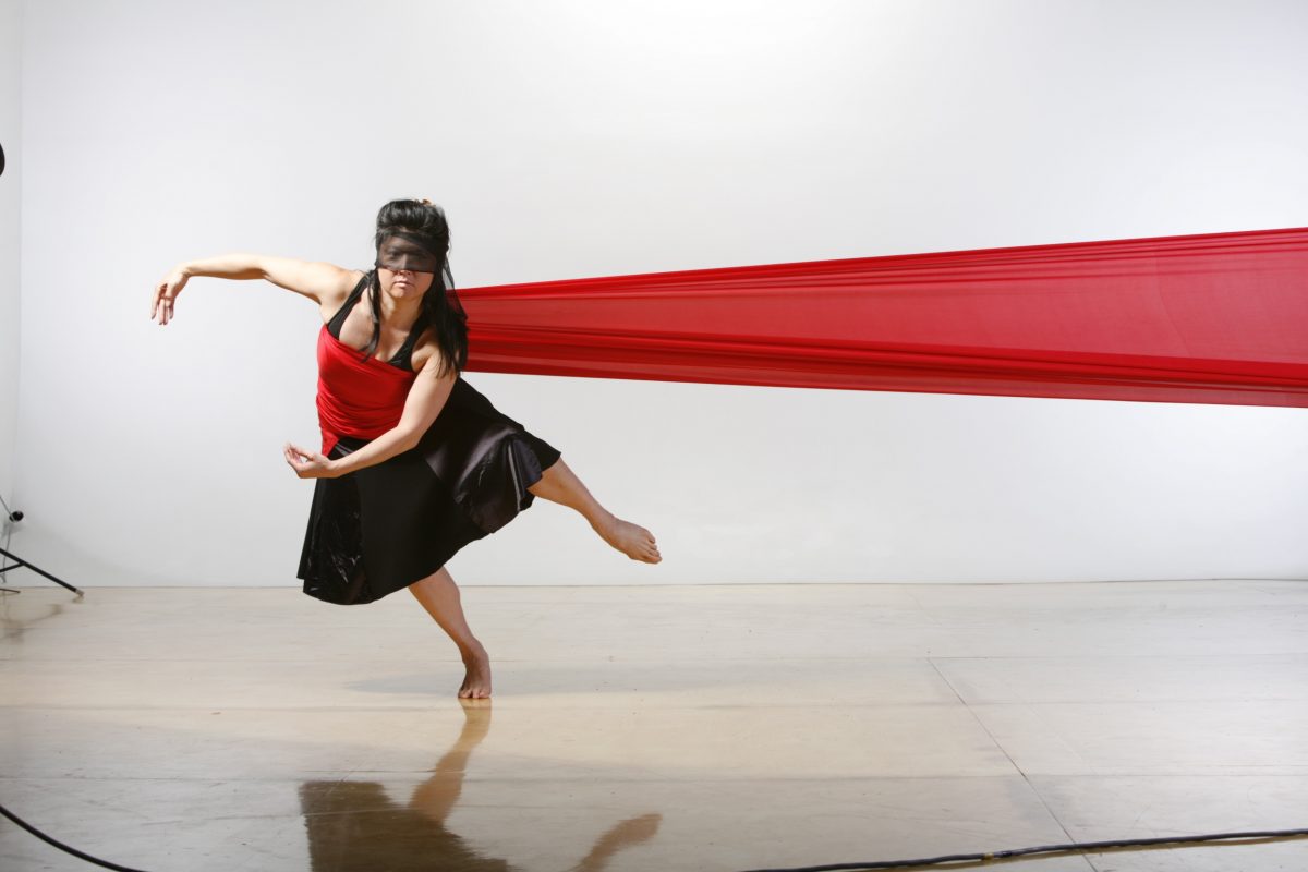 Claudine in a black costume with red fabric wrapped around her