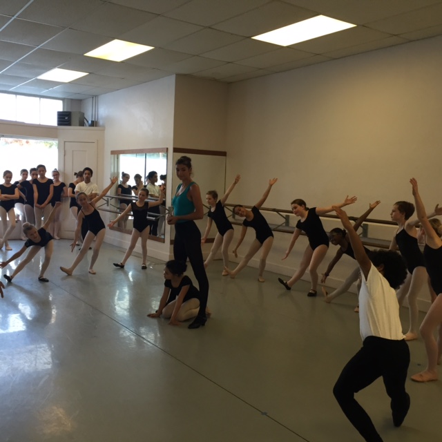 A large group of dancers in rehearsal for the Nutcracker. Rehearsal mistress Jeannine stands in the middle of the group.