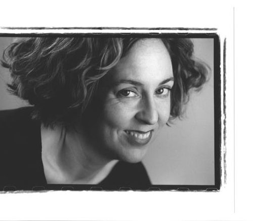 Mary's headshot. In black and white, Mary has short curly hair and smiles at the camera
