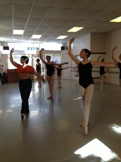 Dancers learning a combination in class. Dancers are slightly in shadow as sunlight streams into the studio.