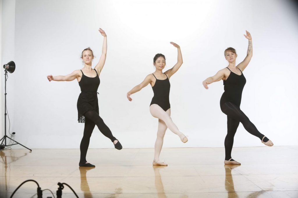 Three adult dancers pose in croise devant.