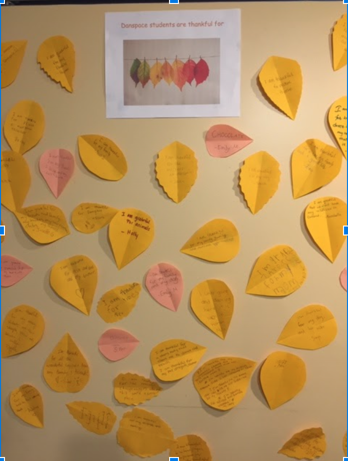 Photo of paper cut into leaf shape with dancers' reflections on what they're thankful for, hung on the door to studio 1.
