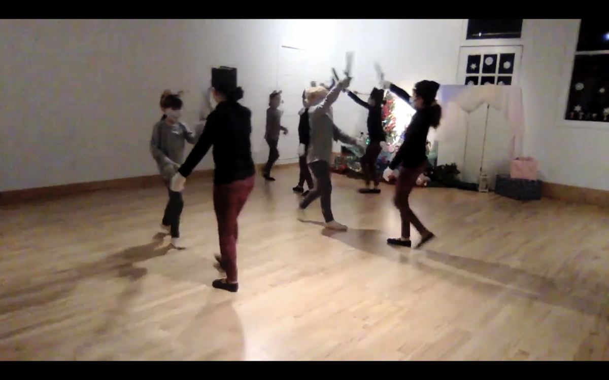 Screenshot of dancers performing the mice and toy soldiers battle from Nutcracker in the studio. 7 dancers in costumes and masks are in motion.