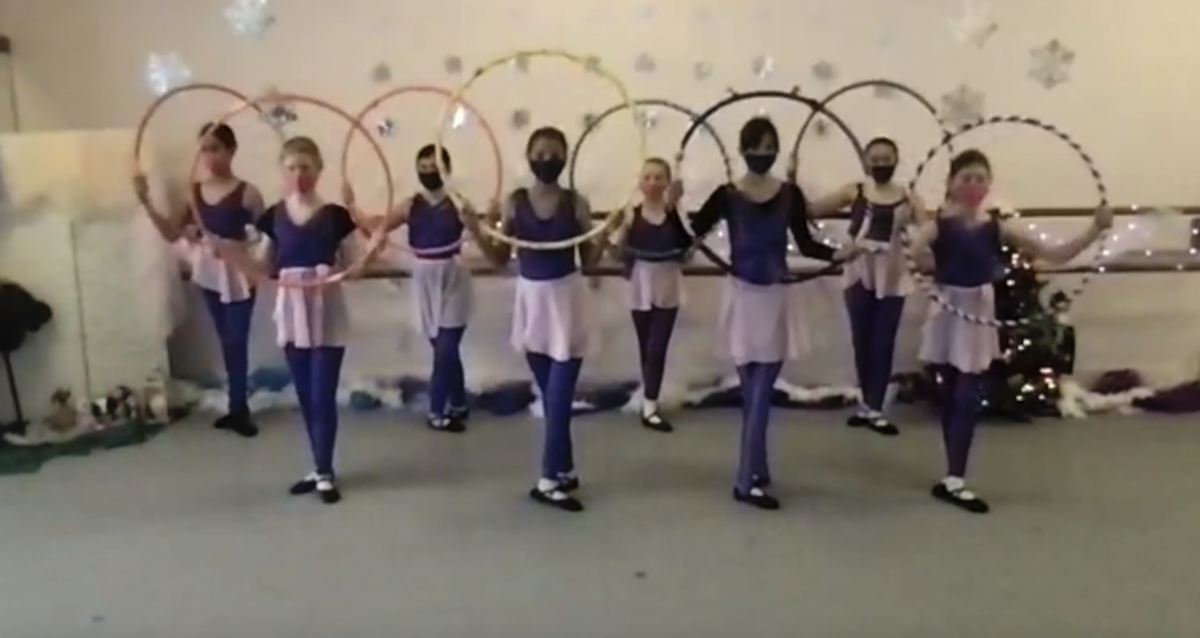 A screenshot of 8 dancers in costumes and masks, holding hula hoops as a prop during an in-studio Nutcracker performance.