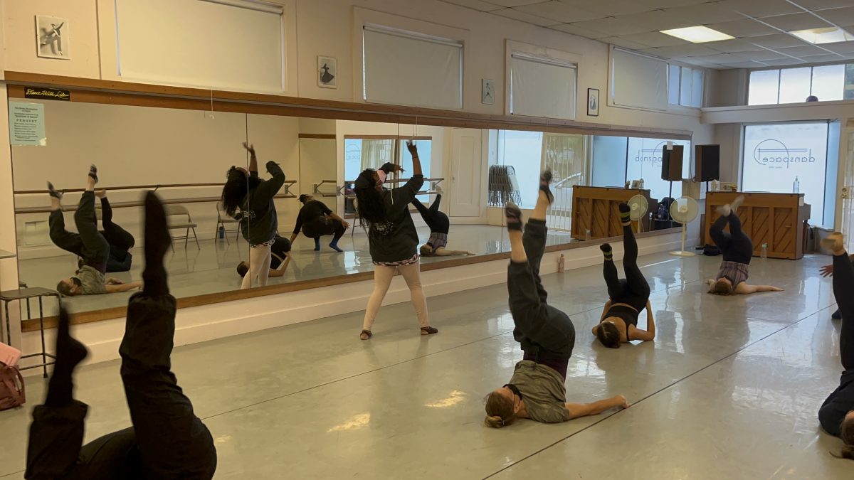 Intermediate / Advanced Modern Jazz students learning choreography. The instructor is in front of the class while the dancers are on the ground, inverted, mid dance.