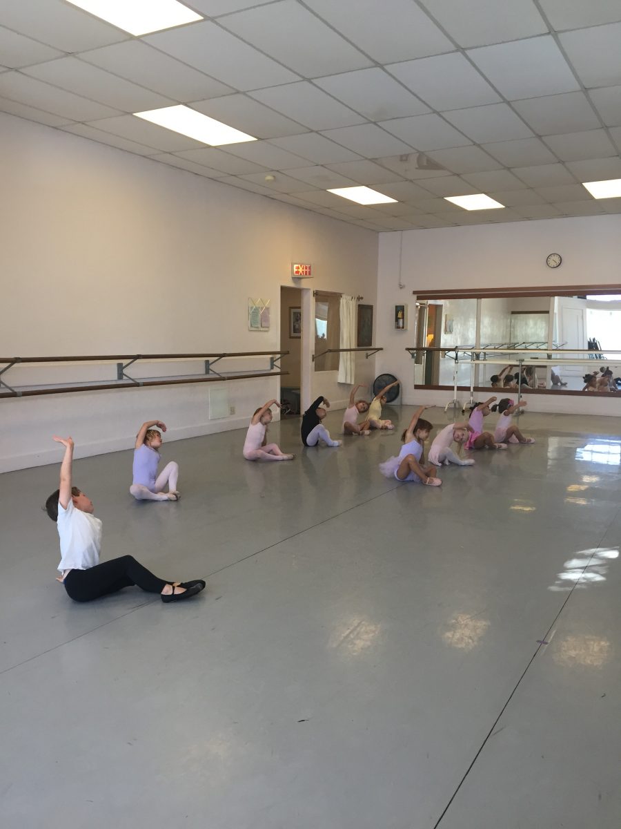 9 young dancers seated in the studio stretching to the side in Danspace's Studio 1
