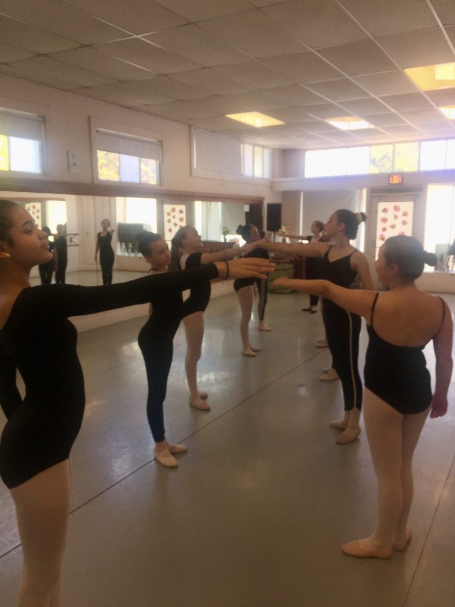 7 dancers pictured in black leotards posing together in Danspace's studio 1 during a summer program performance